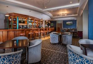 阿克洛Arklow Bay Hotel的一间带桌椅的餐厅和一间酒吧