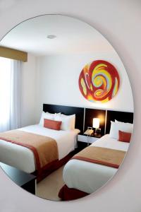 伊拉普阿托Hotel México Plaza Irapuato的配有镜子的客房内的两张床