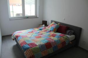 东代恩凯尔克Ruim nieuwbouwappartement oostduinkerke的一间卧室配有一张带五颜六色被子的床