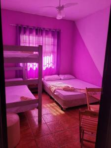 蒙加瓜Pousada das Artes 2的紫色的客房设有两张双层床和一扇窗户。