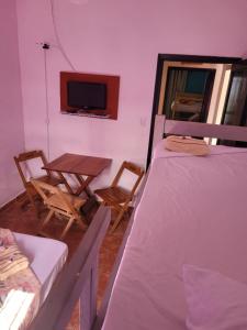 蒙加瓜Pousada das Artes 2的客房设有两张床、一张桌子和一台电视机。
