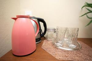 圣特雷莎Loft com Wi-Fi e otima localizacao-Santa Teresa ES的粉红色的水壶和木桌上的两杯玻璃杯