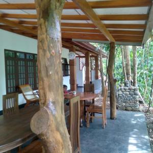 代尼耶耶Sinharaja Gingaga Homestay的一间设有木桌和树木的餐厅