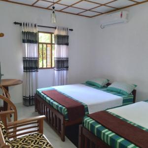 代尼耶耶Sinharaja Gingaga Homestay的一间卧室配有两张单人床和一把椅子