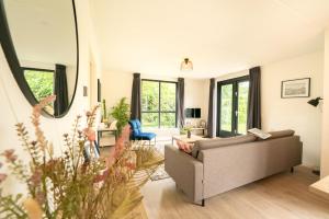 Ewijk6P Vrijstaand Huis met royale tuin en Hottub的带沙发的客厅和部分窗户。