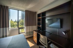 温哥华Gage Suites at UBC的酒店客房配有一张床和一张书桌及一台电视