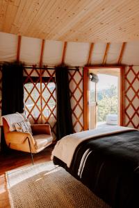 布赖森城Junaluska @ Sky Ridge Yurts的卧室配有床、椅子和窗户。