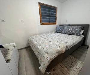 特美好Studio apartman Kod Ruže的一间卧室配有一张带床罩的床和窗户