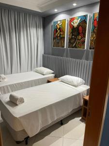 巴雷图斯Condominio Barretos Thermas Park - Condohotel 1242的墙上画作的房间里设有两张床
