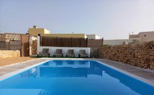 安提瓜Casita rural Molino de La Corte的一个带椅子和石墙的蓝色游泳池