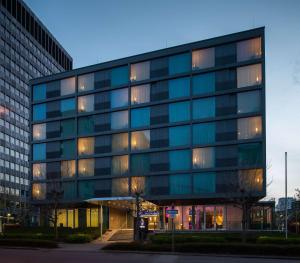 美因河畔法兰克福DoubleTree by Hilton Frankfurt Niederrad的一座带灯的大型玻璃办公楼