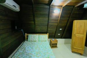 伊塔齐米林Pousada Ecologica Bangalo de Praia的一间小卧室,配有一张床和木墙