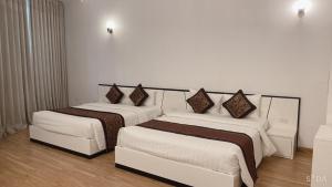北宁K-BOSS Hotel的配有白色墙壁的酒店客房内的两张床