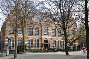 阿姆斯特丹The College Hotel Amsterdam, Autograph Collection的前面有树木的大型砖砌建筑