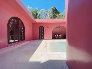 金巴兰VA Villa Jimbaran Bali的粉红色的房子,里面设有游泳池