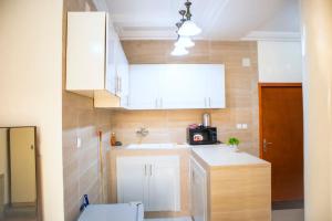布拉柴维尔residence queen house的小厨房配有白色橱柜和水槽
