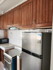 布拉柴维尔appartement nid的厨房配有木制橱柜和不锈钢冰箱。