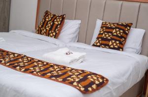 埃尔多雷特VIJIJI HOTEL & CONFERENCE的两张带棕色和白色床单及枕头的床