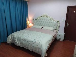 贵阳空中花园民宿 贵阳火车站店的卧室配有一张带蓝色窗帘的大型白色床