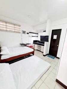 达斯马里尼亚斯Dasma Lofts Hotel near Dela Salle Dasma的白色的客房配有两张床和钢琴