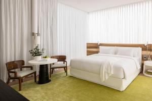 特拉维夫R48 Hotel and Garden的卧室配有白色的床和桌椅