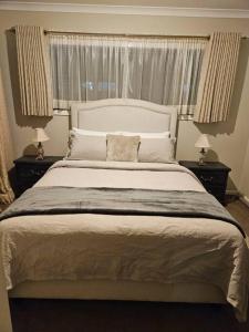 库克角Tranquil home in Point Cook.的一间卧室配有一张带2个床头柜的大型白色床