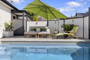 科夫斯港Ellie's Holiday Escape的一个带游泳池和绿色遮阳伞的庭院