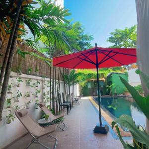 暹粒Siem Reap Urban Boutique Hotel的游泳池旁的天井配有椅子和遮阳伞。