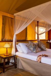 TsavoSentrim Tsavo Lodge的一间卧室配有一张带天蓬和桌子的床