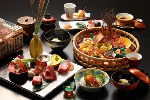 松本玉之汤酒店的餐桌上放有食物盘子和食物篮子的桌子