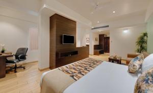 VernaThe Fern Kesarval Hotel & Spa, Verna Plateau - Goa的酒店客房配有一张床、一张书桌和一台电视。
