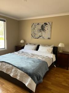 Herne Hill瑟麦切里休闲度假屋的一间卧室配有一张大床、两盏灯和一幅画