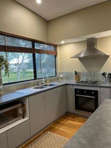 Herne Hill瑟麦切里休闲度假屋的厨房配有白色橱柜、水槽和窗户。
