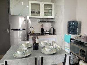 巴淡岛中心Palam Mansion at Apartment One Residence的厨房配有桌子,上面有四个杯子和盘子