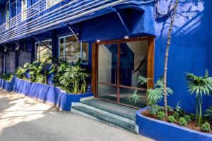 孟买肯普斯角酒店的一座带门和一些植物的蓝色建筑