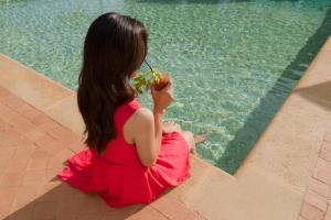 阿格里真托Villa Athena Resort的坐在游泳池旁吃苹果的女人
