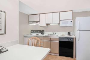 绿湾Hawthorn Extended Stay Hotel by Wyndham-Green Bay的厨房配有白色橱柜和黑色冰箱。