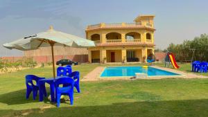 El-Qaṭṭaفيلا للايجار في كمبوند سمر قند的一座带遮阳伞和椅子的房子和一个游泳池
