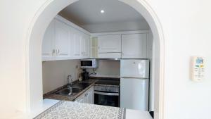 桑帕克Apartamento en el campo de golf Son Parc, Menorca的厨房配有白色橱柜和不锈钢冰箱