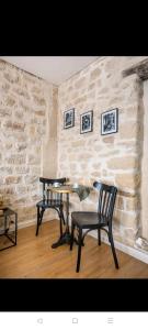 巴黎IMHOST - Amazing architect studio Père Lachaise的石墙客房内的两把椅子和一张桌子