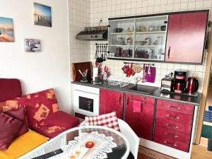 科尔平塞Ferienwohnung Loddin USE 2801的一间设有红色橱柜和一张桌子的小厨房