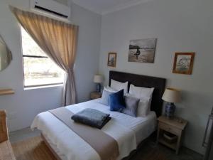 普利登堡湾Matjesfontein Estate Keurbooms Chalet的卧室配有带蓝色枕头的大型白色床