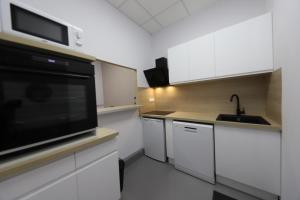 马赛Loft 250m2 avec écran led géant de 10m2的厨房配有白色橱柜和黑微波炉