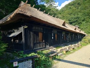 仙北民宿 鳳凰館 座敷童子のわらべ唄的一座带茅草屋顶的老房子,前面设有长凳