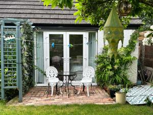 贝尔法斯特Garden Snug的房屋前设有带2把椅子和1张桌子的庭院。