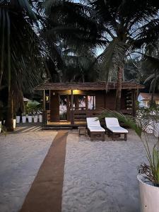 曼德姆Mamagoa Beach Resort的一个带两个长椅的度假村和一座棕榈树建筑
