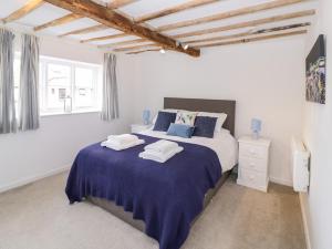 珀肖尔Chapel Cottage的白色卧室配有一张带蓝色床单的大床