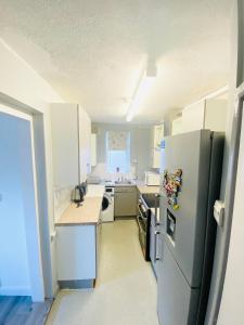 清福德London Studio的厨房配有白色橱柜和冰箱。