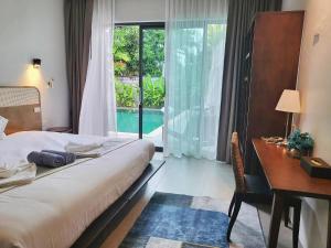 邦涛海滩E villa near bangtao beach ,普吉高端社区邦涛区度假村私人泳池别墅的一间卧室配有一张床、一张书桌和一个窗户。