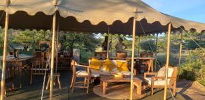 Kwa MhindaMakubi Safari Camp by Isyankisu的一个带桌椅和桌子的大型帐篷